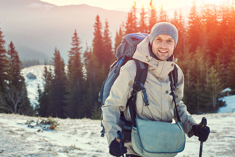 Mężczyzna z plecakiem i kijkami podczas trekkingu