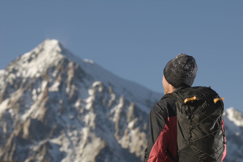 Mężczyzna z plecakiem patrzący na ośnieżone góry